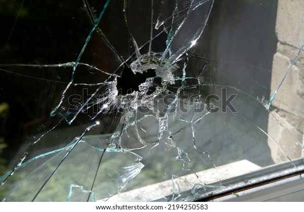Window glass shattered by a shell fragment.\
Broken window glass\
close-up.