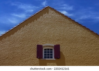 Window High Up In A Yellow Stucco Building Under Blue Sky