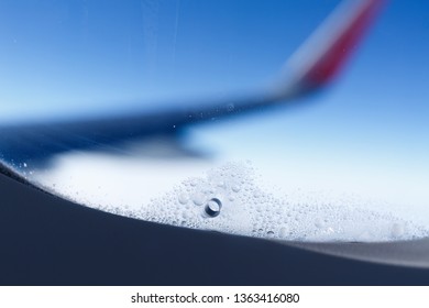 window with a hole to relieve pressure between the Windows of the aircraft with frost around, close-up on the background of the wing of the aircraft