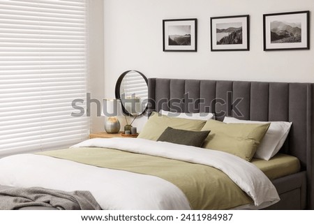 Window with horizontal blinds and comfortable bed in room