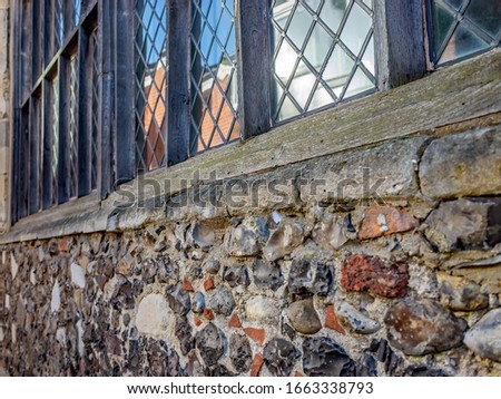Window with intricate iron work surrounded by wooden timber frame in a traditional building made of stone