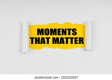 A window is made in the paper, where on a yellow background the inscription - Moments That Matter