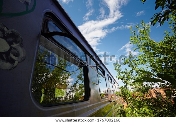 The window of the old passenger car in the\
background of tree branches and\
sky