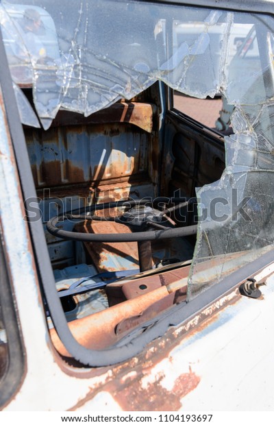 window of old rusty car with broken glass and\
steering wheel.