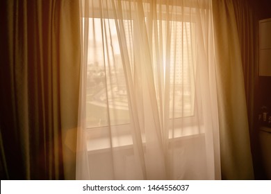window is open in house, evening light fills room of apartment, bright ray of sun shines through window, wind stirs curtain, airing bedroom before bedtime