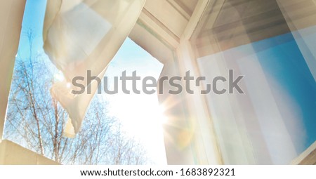 Window is open wind blows curtain sun shining through window blue sky background