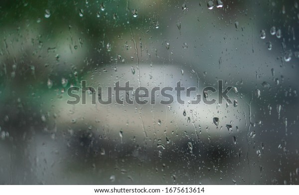 Window overlooking a rainy street. Gloomy evening\
weather with a view of the road. Drops on glass and bokeh from\
cars. Stock background for\
design