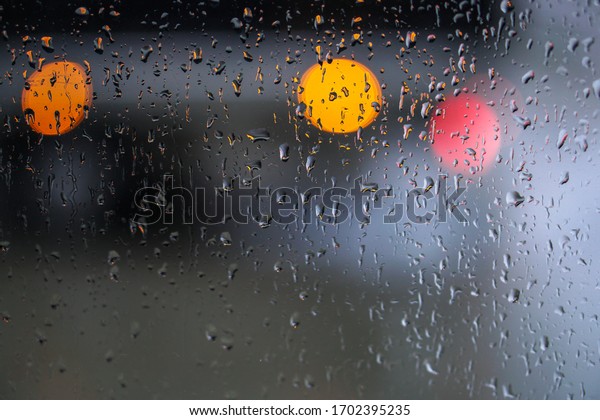 Window\
overlooking a rainy street. Gloomy evening weather with a view of\
the road. Drops on glass and bokeh from cars. \

