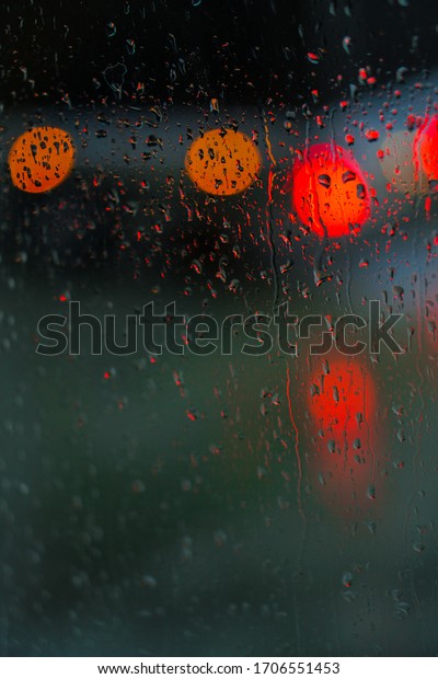 Window overlooking a rainy street. Gloomy evening\
weather with a view of the road. Drops on glass and bokeh from\
cars. Stock background for\
design