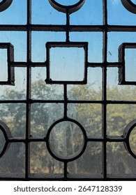 A window with a pattern of squares and circles. The window is dirty and the pattern is blurry