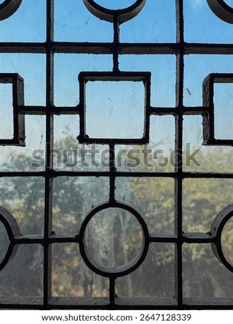 A window with a pattern of squares and circles. The window is dirty and the pattern is blurry