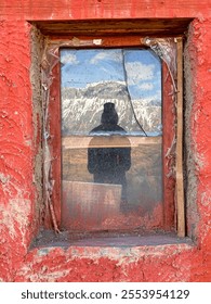 A window with a person's reflection in it. The reflection is blurry and the person is wearing a hat