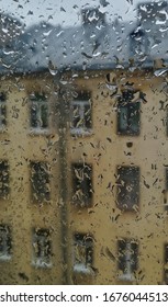 Window with raindrops and view of the old building on a cloudy day