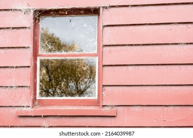 Window And Reflection In Glass In Red Spiderweb Covered Weatherboard Wall