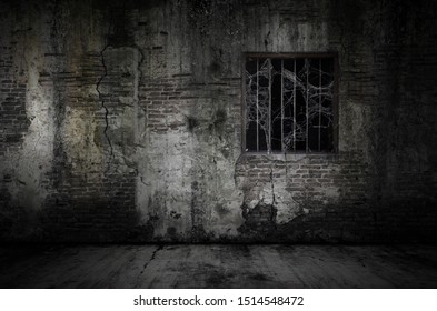 Window and rusty bars covered with cob web or spider web on prison old bricks wall and dusty floor, concept of horror and Halloween