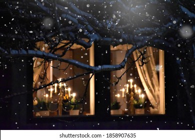 Window with snow flakes in the winter and christmas time, cold freezing weather, season, romantic, candles in the night,  tree and branches, silent, light, holy, celebration, new year, christmas eve 