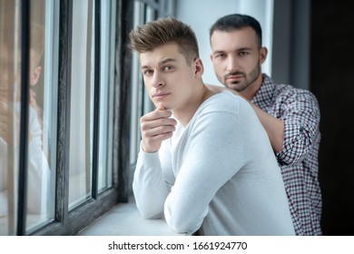 At the window. Two young men standing near the window