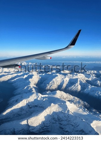 Window view from a flight looking over new zealand south island scenery. Snow mountain from aircraft flying into queenstown nz. Winter flying over glacier landscape.