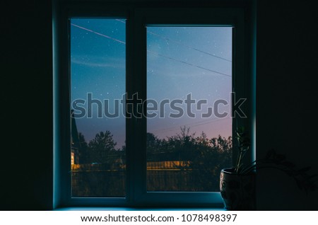 WIndow with view on night city sky with stars and tree