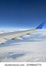 window view of plane wing over clouds