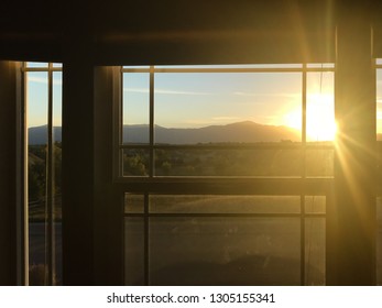 window view of sun setting over rocky mountain range