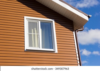 Window In The Wall Of Brown Vinyl Siding