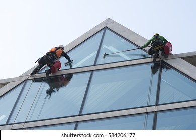 Window Washers Cleaning The Glass Facade Of A Modern Building, High Risk Work.