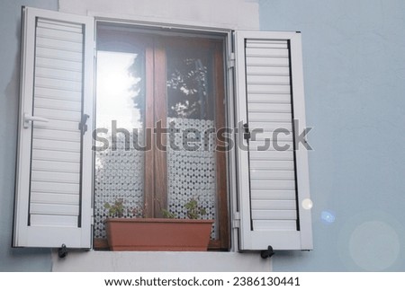 Window with white open shutters sun reflection