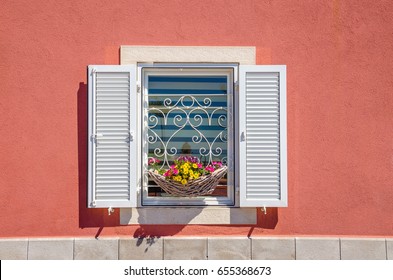 Window with white shutters and beautiful blooming flowers against a red wall  - Powered by Shutterstock