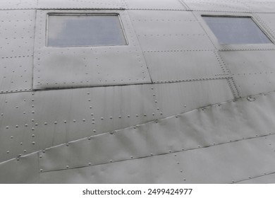 Windows in Airplane Fuselage. Two square fuselage windows on the side of an old green transport aircraft.
