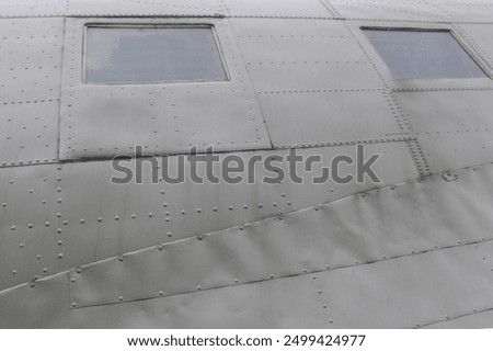 Windows in Airplane Fuselage. Two square fuselage windows on the side of an old green transport aircraft.