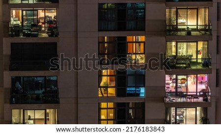 Windows of apartment building at night timelapse, the light from illuminated rooms of houses. Urban landscape of the glowing skyscrapers