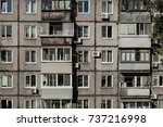 Windows and balconies of a dilapidated house made of concrete. Several floors, many apartments. Bad living conditions, terrible housing, cheap rooms.
