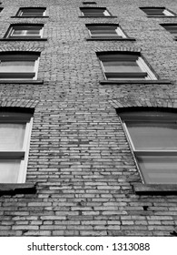 Windows in a brick wall on the side of an urban apartment building.