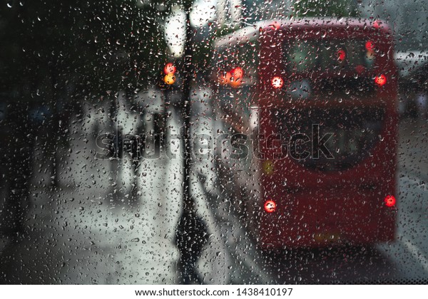  The windows\
is focused and a double decker bus is visible behind along with a\
couple walking under the rain.