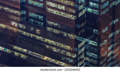 Windows In High-rise Office Building Exterior In The Late Evening With Glowing And Blinking Interior Lights On Timelapse. Aerial Top View