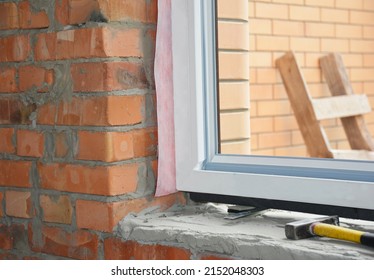 Windows installation. Inserting a upvc plastic window frame in a newly constructed brick house. - Shutterstock ID 2152048303