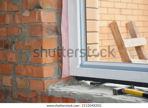 Windows installation. Inserting\
a upvc plastic window frame in a newly constructed brick\
house.