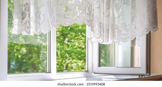 Windows And Lacy Curtains Of White Colours Against Blurry Green Garden Trees Under Bright Sunlight On Summer Day