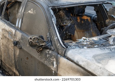 Windows shatter from the explosion. Setting fire to cars of a terrorist attack. Remains of a burned car. Burned out car on roadside down in the middle of the street. Burnt new car, vandalism, mafia.