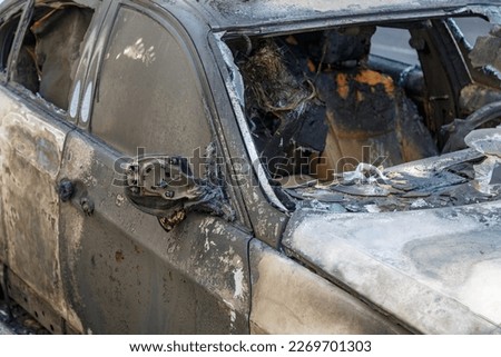 Windows shatter from the explosion. Setting fire to cars of a terrorist attack. Remains of a burned car. Burned out car on roadside down in the middle of the street. Burnt new car, vandalism, mafia.