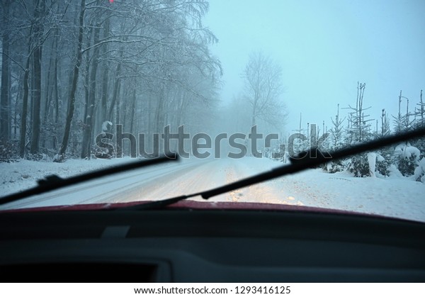 Windscreen wipers. Driving the car\
in the winter. View from the interior of a car on a snowy road by\
the eyes of the driver. Concept for driving safety in the\
winter.