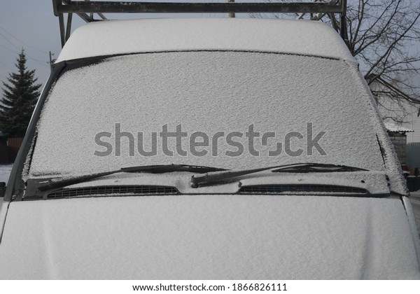  Windscreen wipers and a snow covered car or\
bus.winter season. front view.