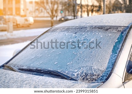 Windshield covered with ice, frozen glass and wiper. Car window under layer of ice. Frost on car glass. Low visibility, dangerous driving in winter season.