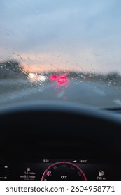Windshield full of raindrops while driving on a road rainy weather at dusk driver's point of view
