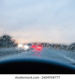 Windshield full of raindrops while driving on a road rainy weather at dusk driver's point of view