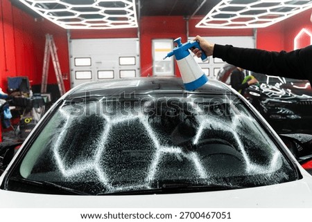 Windshield preparation with a special solution before film application. Detailer spray a glass prep liquid to remove dust, grease, and debris before applying protective film