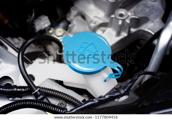 Windshield washer fluid cap with blue color\
in engine room of car, automotive part\
concept.