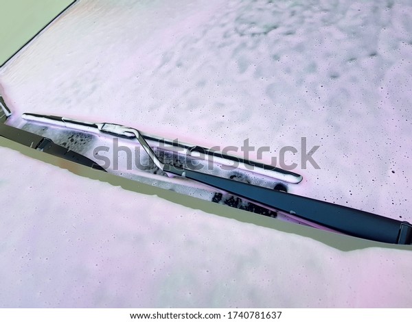 Windshield with a\
wiper blades coated with active washing foam for washing a dirty\
car, closeup side view\
nobody.