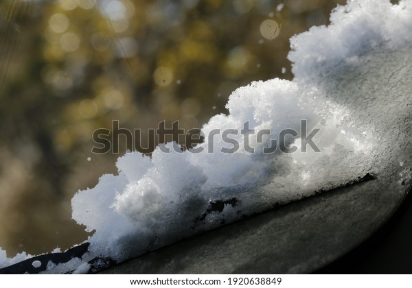 Windshield wiper\
blades on vehicle, clearing off heavy layer of snow. Pile of snow\
on car window. Isolated\
closeup.